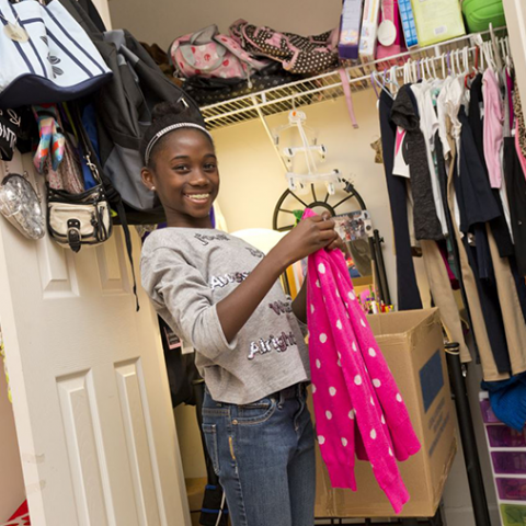 Girl in closet with clothes to donate